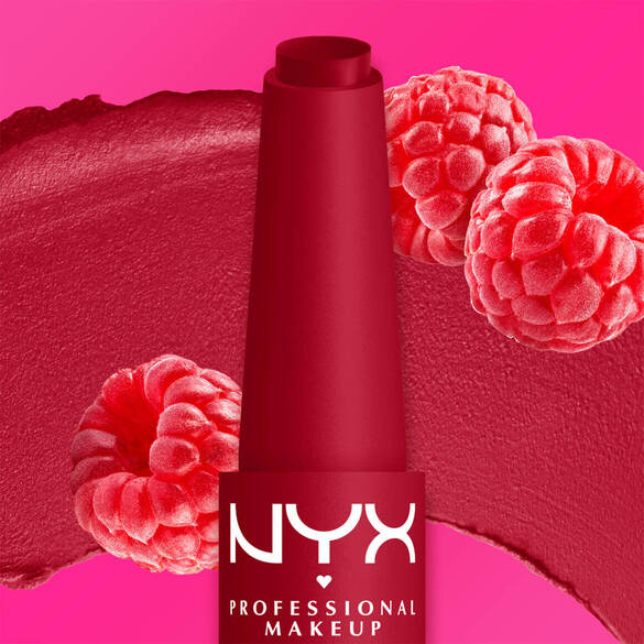 Un vibrante labial de tono frambuesa se muestra junto a frambuesas frescas y una muestra de textura del labial sobre un fondo rosa, resaltando el color y la inspiracion en las frutas.