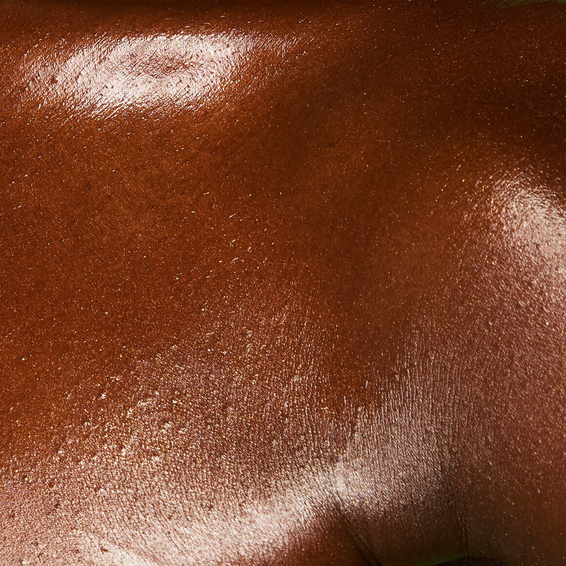 Image of the model’s chest after applying NYX Professional Makeup Fat Oil Body Oil in Caramelt Mami, showing a gold, glowy finish.